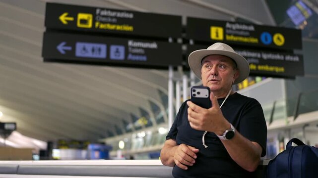 Mature tourist man video calling at airport terminal
