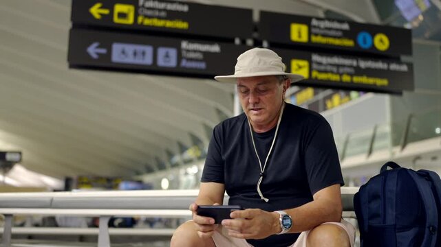 Mature traveler using smartphone while waiting in airport terminal