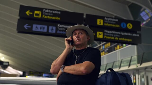 Mature tourist man talking on phone at airport terminal