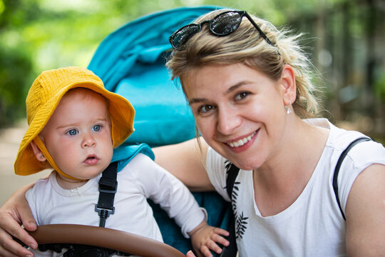 Loving Mother Kissing Her Baby in a Stroller Outdoors