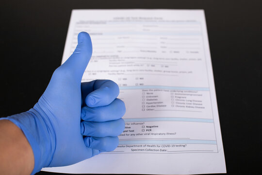 Medical Professional in Blue Glove Giving Thumbs Up Over Diagnostic Test Form