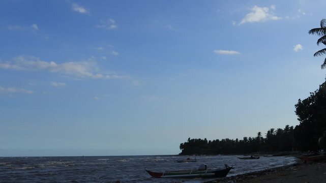 Small waves move slowly on the beach, fishing boats on the shore