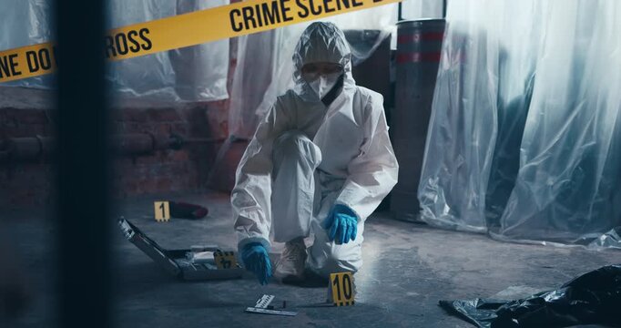 Crime scene investigator carefully holds and inspects a cartridge casing during forensic examination.
