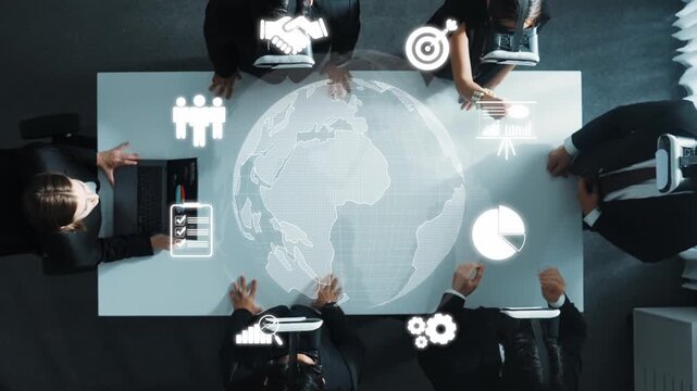 A diverse business team collaborates around a modern table, utilizing technology and digital data visualization tools to strategize on global objectives and innovative solutions. Raster