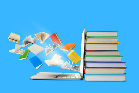 Books are stacked beside a laptop with pages flying up