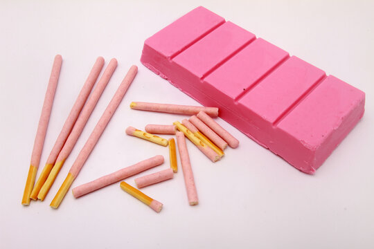 pink stick biscuits with pink chocolate bar on white table