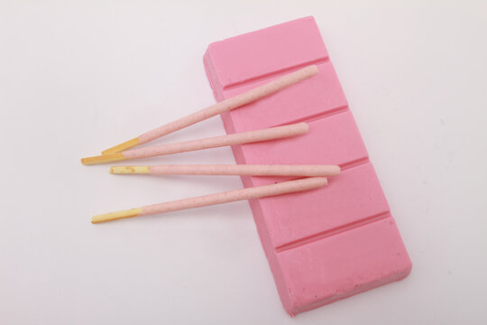pink stick biscuit with chocolate bar on white table
