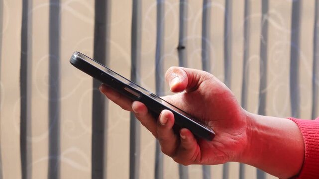 Asian man's hand spraying sanitizer and wiping a smartphone screen with a microfiber cloth. Cleaning and disinfecting a mobile phone to remove germs and bacteria.