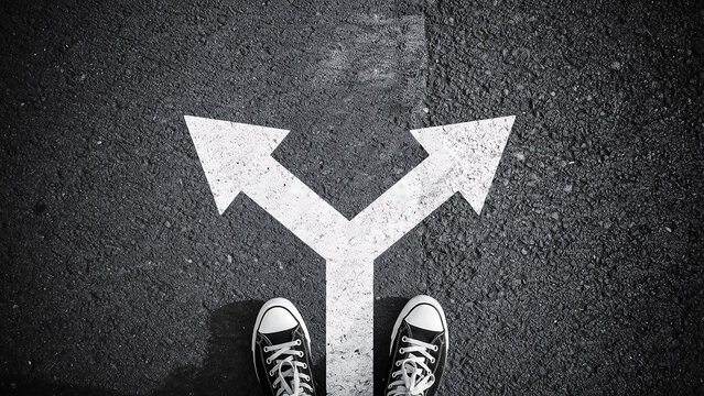 Choosing the right direction conceptual view of sneakers on a road split decision direction sneakers lifestyle planning opportunity strategy motivation uncertainty
