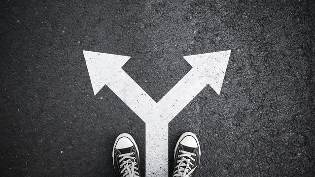 Person standing at a y-shaped path fork in the road choosing a direction with direction decision sneakers standing perspective crossroads motivation adventure opportunity strategy