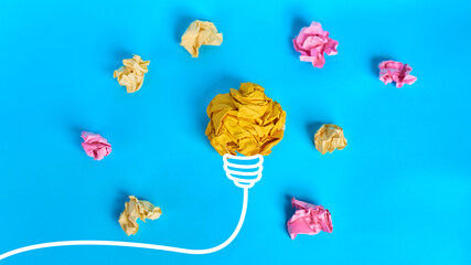 Crumpled yellow paper light bulb surrounded by colorful paper balls on blue background  © kaliel