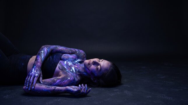 Fluorescent body paint on woman lying down with galaxy theme art