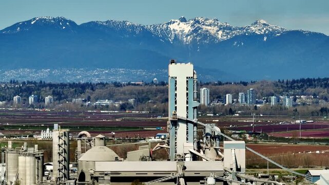 Delta, Richmond, British Columbia, Canada - A Shipping and Industrial Area Along the Fraser River With the Coast Mountains in the Background - Orbit Drone Shot