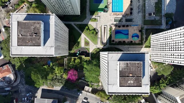 Lateral tracking drone shot showcasing luxury residential buildings with swimming pools and tennis courts alongside a modest residential complex, near Villa-Lobos Park in S&atilde;o Paulo