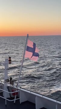 Finnish flag waving in the wind on a ferry crossing the sea, national flag of Finland vertical video