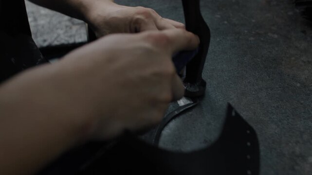 Hands cutting leather shoe parts on a workbench in a shoemaking workshop