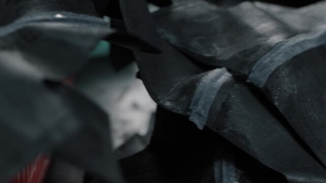 Stack of dark leather shoe pieces prepared for assembly in a workshop setting