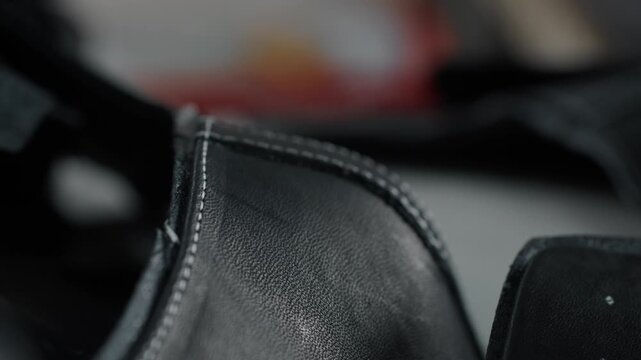 Closeup of black leather shoe upper with visible stitching in workshop setting