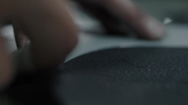 Close-up of hands cutting leather material for shoe production in workshop setting