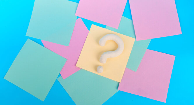 White question mark centered on yellow note among colorful pastel notes on blue background
