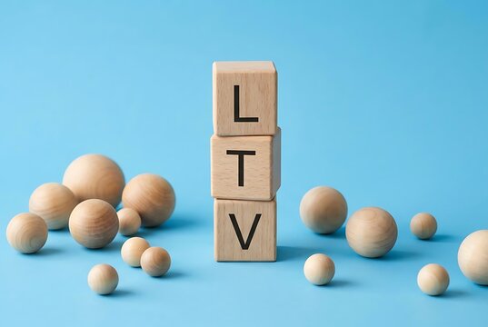 Wooden blocks spell LTV surrounded by spheres on blue background. Business and Finance concept