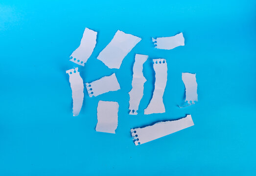 Collection of blank torn notebook paper scraps on bright blue background

