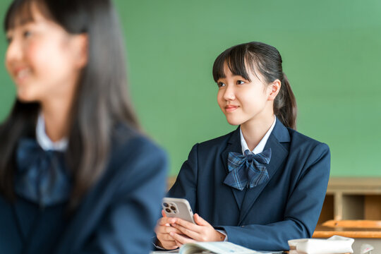 Elementary, middle, and high school students taking online classes using smartphones in school classrooms (ICT education)