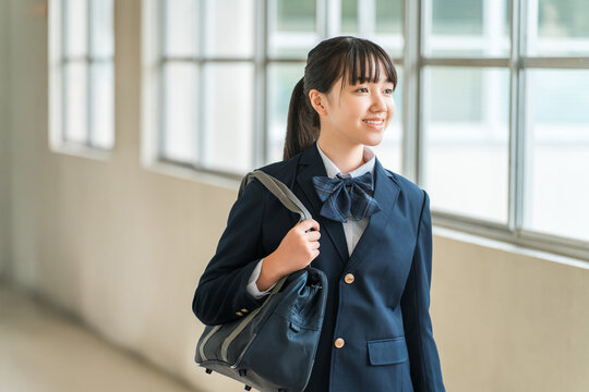 Elementary, middle, and high school girls in uniform walking down a school corridor.