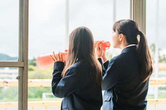 Women (students, junior high school girls, high school girls) cheering from classrooms and school buildings with megaphones.