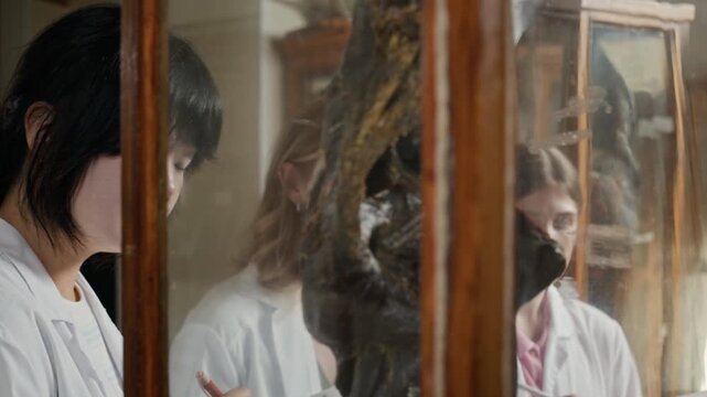 Multiethnic young adult medical students taking notes while senior Caucasian professor explaining anatomical specimen in museum. Ideal for medical school advertising and educational content
