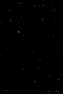 Sparse falling snow on black background, isolated overlay effect for editing.