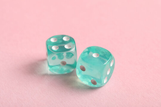 Turquoise game dices on pink background
