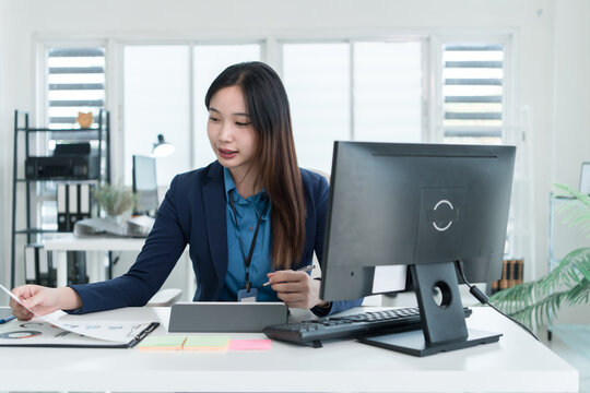 Young Businesswoman Working at Office Desk While Managing Documents and Mobile Communication.
