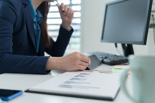 Young Businesswoman Working at Office Desk While Managing Documents and Mobile Communication.