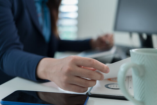 Young Businesswoman Working at Office Desk While Managing Documents and Mobile Communication.
