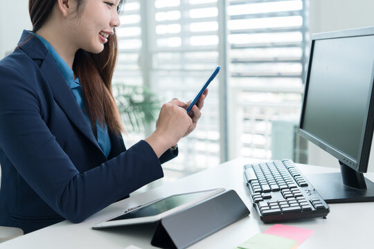 Young Businesswoman Working at Office Desk While Managing Documents and Mobile Communication.