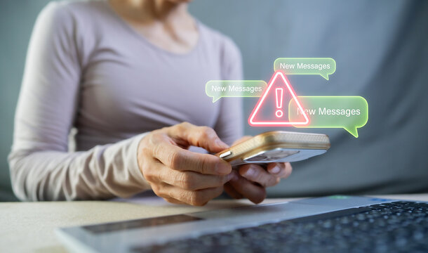Woman holding smartphone with warning alert and new message notification, cyber security scam concept