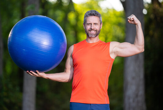 mature man hold Fitness ball. Outdoor workout. Healthy fitness routine. Active lifestyle outdoors. Exercise ball supports training. Fitness outdoors daily. Stability ball exercise. Healthy lifestyle.