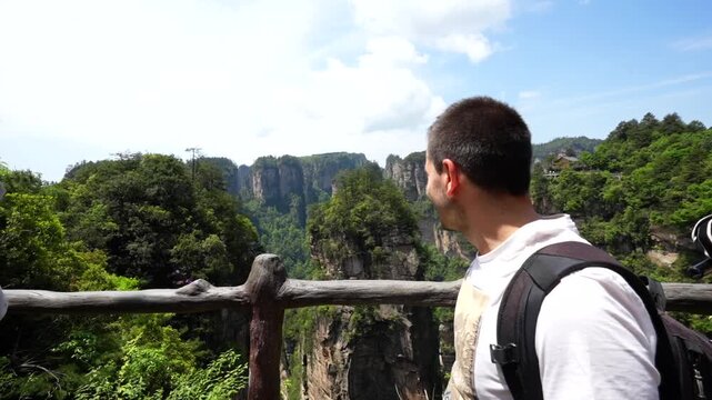 Young man filming himself on vacation pointing at the Hallelujah Mountain in Yuanjiajie