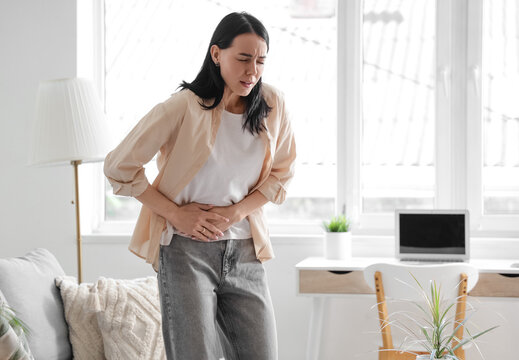 Young woman suffering from severe abdominal pain at home