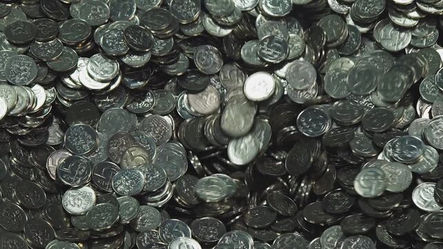 Coins pile up in a large heap to show a massive amount of currency and financial assets spread out across the table during a counting process that highlights monetary gain and economic prosperity.
