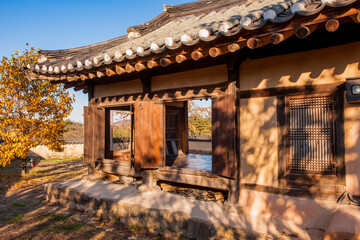 Fototapeta premium Exterior Perspective View of Traditional Korean Hanok Open Wooden Windows and Autumn Foliage Under Warm Sunlight and Shadows