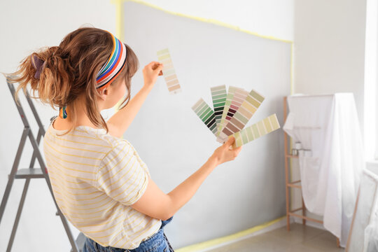 Young woman with paint color palettes during repair in room