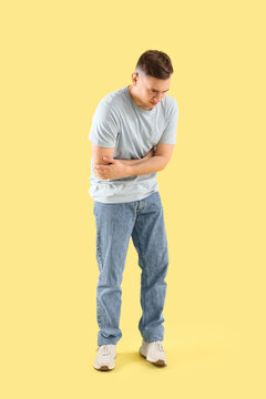 Young man suffering from bellyache on color background