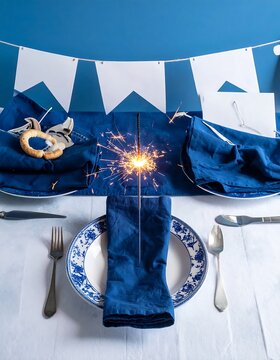 Festive table setting with blue napkins and a lit sparkler.