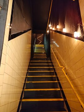 Acesso interior em estilo industrial com degraus iluminados e revestimento de azulejos no Centro do Rio de Janeiro