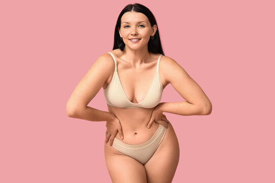Body positive young woman in underwear smiling on pink background