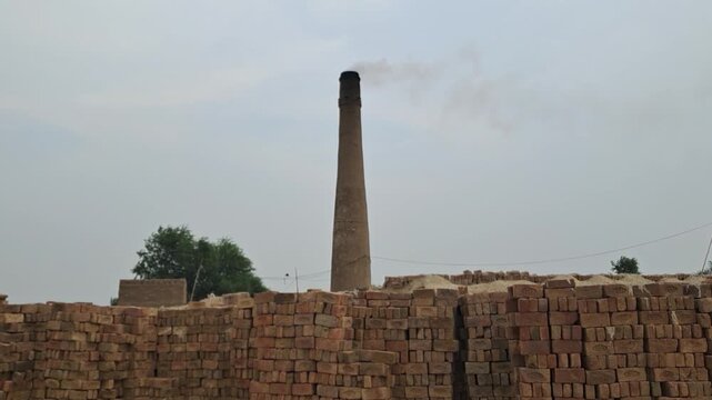 Working Brick Kiln with Stacked Clay Bricks Under Cloudy Sky