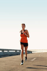 Obraz premium Active, woman and running for fitness on bridge with health training, morning cardio or endurance. Space, road and athlete with highway jog for exercise routine, wellness challenge or workout stamina