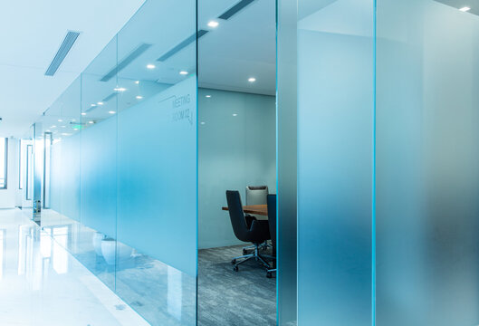 Contemporary corporate office corridor with frosted glass partitions and modern meeting room corridor partition